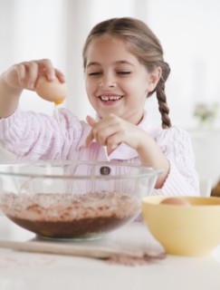 Young girl cracking egg. Photographer: Jamie Grill