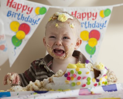 Baby covered in birthday cake. Photographer: Mike Kemp
