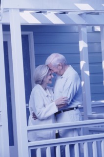 Elderly couple embracing on porch. Photographer: Rob Lewine