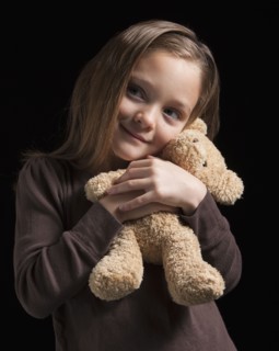 Young girl hugging teddy bear. Photographer: Mike Kemp