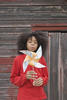 Girl blowing toy windmill. Photographer: Pauline St.Denis