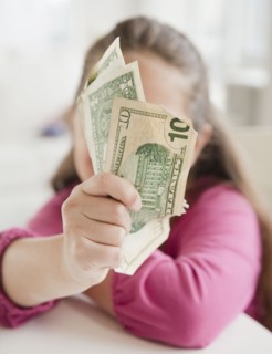 Young girl holding money. Photographer: Jamie Grill