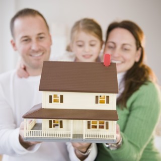Family holding model house. Photographer: Jamie Grill