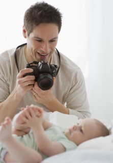 Father taking photograph of baby.