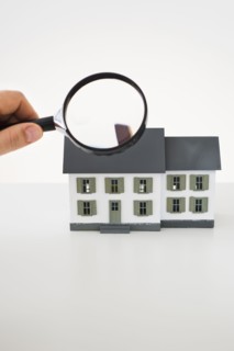 Looking at toy house with magnifying glass.