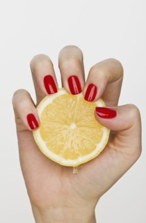 Hand holding slice of lemon.