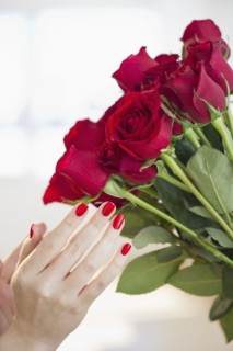 Red roses and hand with red nail polish.