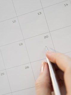 Writing with pen on calendar.
