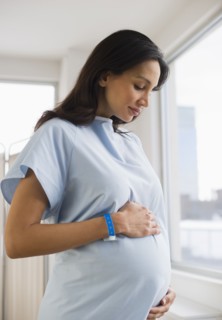 Pregnant woman wearing hospital gown.