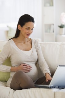 Pregnant woman looking at laptop.