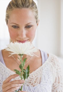 Woman smelling a white flower.