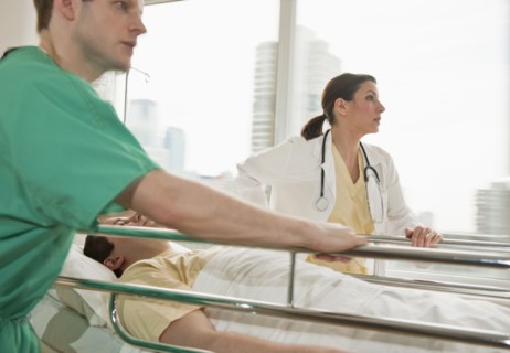 Healthcare workers pushing gurney in emergency room.