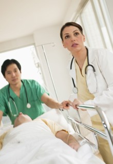Healthcare workers pushing gurney in emergency room.