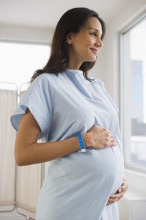 Pregnant woman wearing hospital gown.