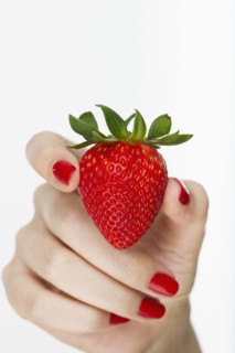 Hand holding red strawberry.