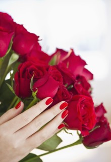 Hand holding bouquet of red roses.