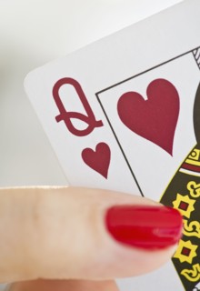 Hand holding a queen of hearts card.