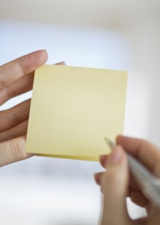 Hands holding notepad and pen.