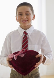 Young boy holding a box of chocolates.