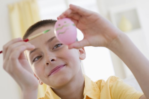Young boy decorating an Easter egg.