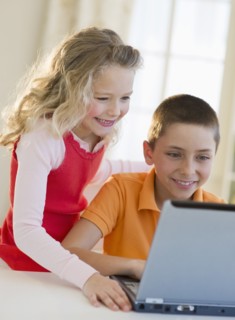 Siblings looking at laptop.
