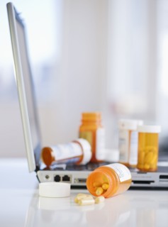 Bottles of prescription pills on laptop. Photographe : Jamie Grill