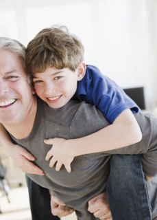 Father giving son piggy back ride. Photographe : Jamie Grill