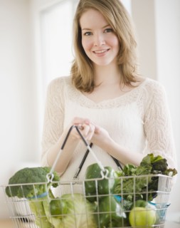 Woman holding basket of green vegetables. Photographe : Jamie Grill