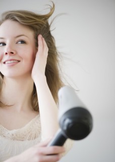 Woman blow drying hair. Photographe : Jamie Grill
