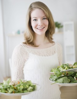 Woman carrying plates of salad. Photographe : Jamie Grill