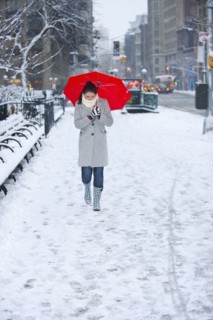 Woman walking with red umbrella on snowy day. Photographe : Daniel Grill