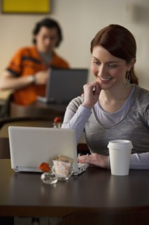 Woman working on laptop in coffee shop. Photographe : Daniel Grill
