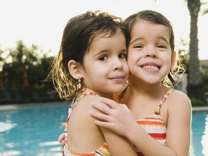 Sister embracing beside pool.