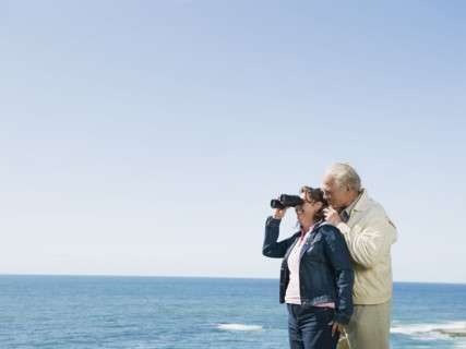 Couple looking at ocean with binoculars.