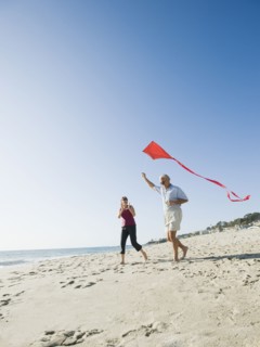 Couple flying kite on beach.