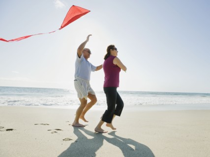 Couple flying kite on beach.