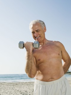 Man exercising with dumbbell on beach.