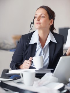 Businesswoman drinking coffee at desk. Photographe : momentimages