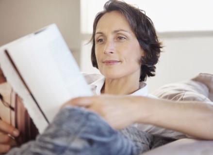 Woman reading on couch. Photographe : momentimages