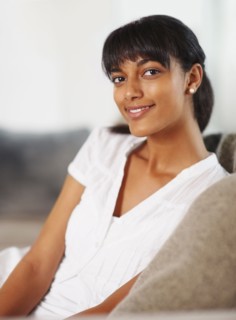 Young woman sitting on couch. Photographe : momentimages