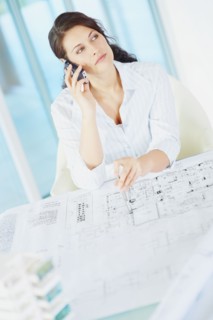 Woman looking at blueprints. Photographe : momentimages