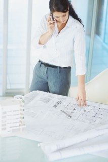 Woman looking at blueprints. Photographe : momentimages