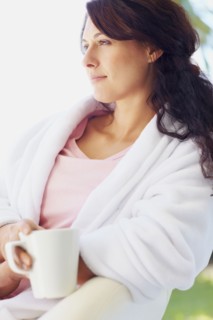 Woman in bathrobe drinking coffee. Photographe : momentimages