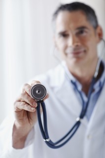 Doctor holding stethoscope. Photographe : momentimages