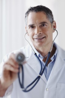Doctor holding stethoscope. Photographe : momentimages