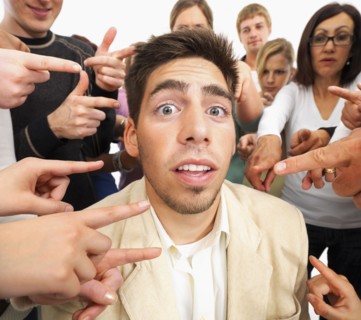 Group of people pointing at one person. Photographe : momentimages