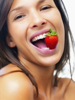 Woman eating strawberry. Photographe : momentimages