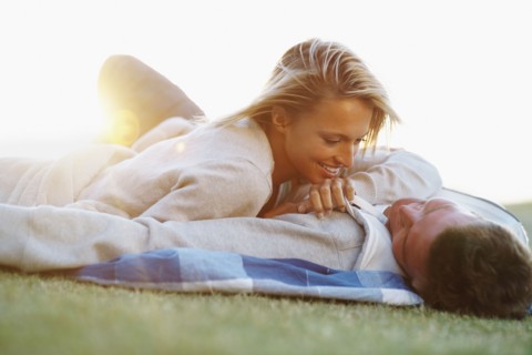 Couple lying down on picnic blanket. Photographe : momentimages
