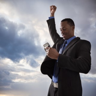 Happy businessman holding a mobile phone. Photographe : Mike Kemp