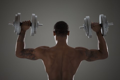 Physically fit man lifting dumbbells. Photographe : Mike Kemp